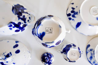 White plates, pots, and cups, with blue inky splat decoration