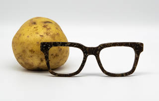 A potato with a pair of square framed glasses in front of it