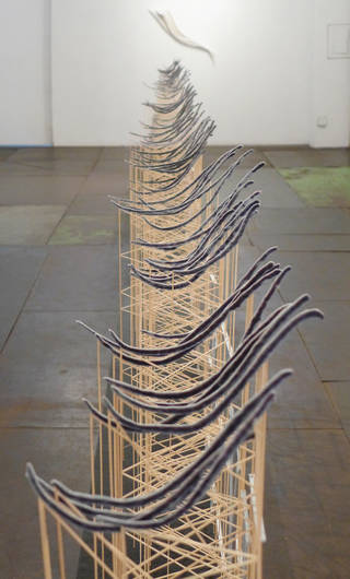 A mesh of wooden supports supporting black curved shapes that lie on top