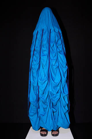Model wearing a bright blue ruched shroud covering her entire head and body, except her feet