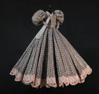 Dress with large puff sleeves and very full skirt on a black background. Busy pattern on dress in brown, black and fawn