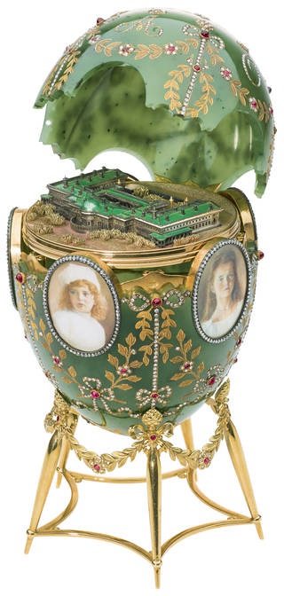 Green Faberge easter egg on stand with open lid showing a model of the Alexander Palace inside