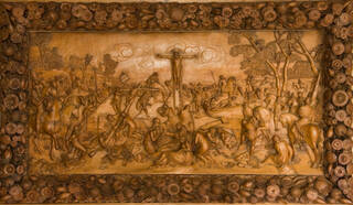 Mid-brown carved wooden panel with floral border depicting a crucifixion.