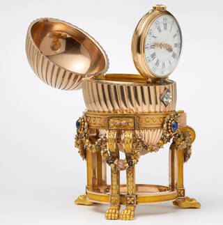 gold egg on a gold stand with clock inside, shown open