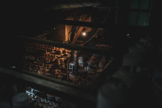 Dimly lit photograph of the inside or a pottery filled with unfired pots. 