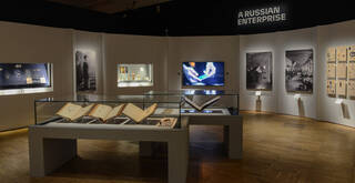 Room with open books on a table and photographs on the wall.