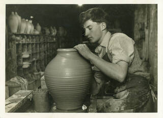 Black and white photo of a young man throwing a pot on a wheel