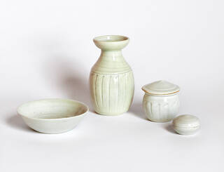 Four pale cream porcelain vessels on a pale pink background