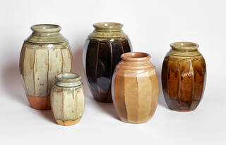 Five pottery jars with simple decoration on a white background