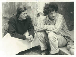 Black and white photo of a man and woman sat on some steps