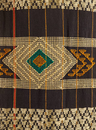 Detail of fabric with diamond-shaped pattern in greens, browns, oranges and beige