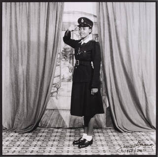 Black and white photo of woman in police uniform saluting 