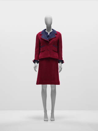 Dark red tweed suit with dark blue lining and two pockets on the front. Accompanied by a slightly above knee-length matching red skirt