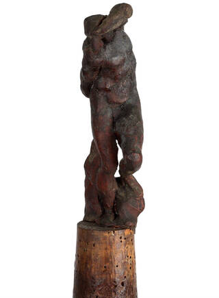 reddish brown waxy human-like form on cylindrical cork base