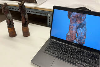 two small sculptures in reddish-brown and a computer screen with a partial image of the sculpture on a blue background