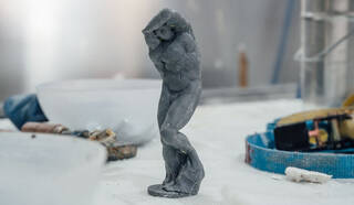 small blue sculpture of a figure on a white table top