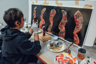 woman sat at a table painting a small model 