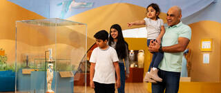 Family smiling and pointing as they explore the Young V&A Making Egypt exhibition
