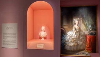 Peach interior with a white sculpture bust and painting portrait of a woman