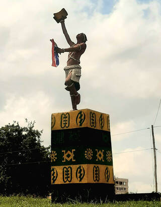 Figure of a man standing on a plinth holding a stool above his head