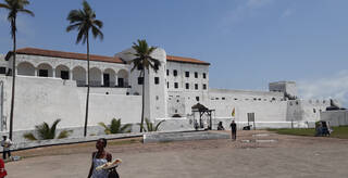 White building with terracotta tiled roof with two palm trees in front