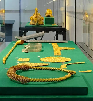 Gold objects on display in a cabinet with a green base