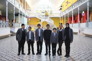 A group of young people stand smiling in the Young V&A