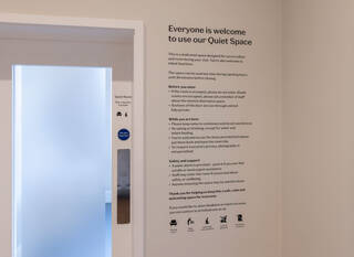 Guidelines for using the Quiet Rooms in black lettering on a white wall. Pictographs indicate you can rest, change nappies, and use the rooms for multi-faith contemplation. You cannot eat or use your phone in the rooms.