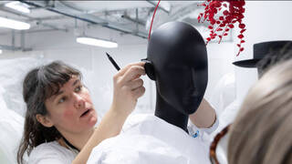 woman working with a pen in hand on a black mannequin head