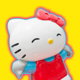 A photo of a Hello Kitty model with her eyes shut wearing a red bow set against a yellow background with a blue and red halo.